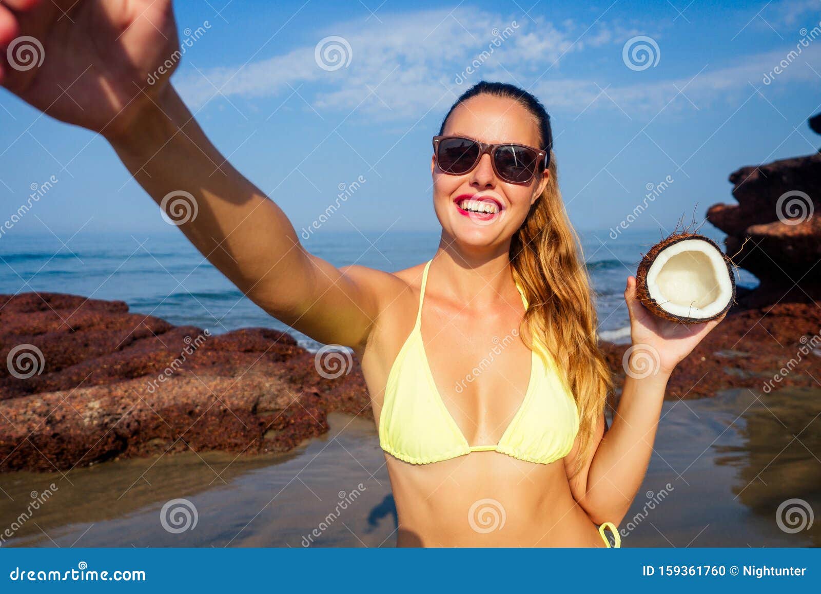 Liberté Jeune femme en maillot de bain jaune sexy tenant une noix de coco à la main sur une plage femme blonde photographiée. Liberté Jeune femme en maillot de bain jaune sexy tenant une noix de coco à la main sur une plage femme blonde photographiant selfie smartphone tourisme maritime spa