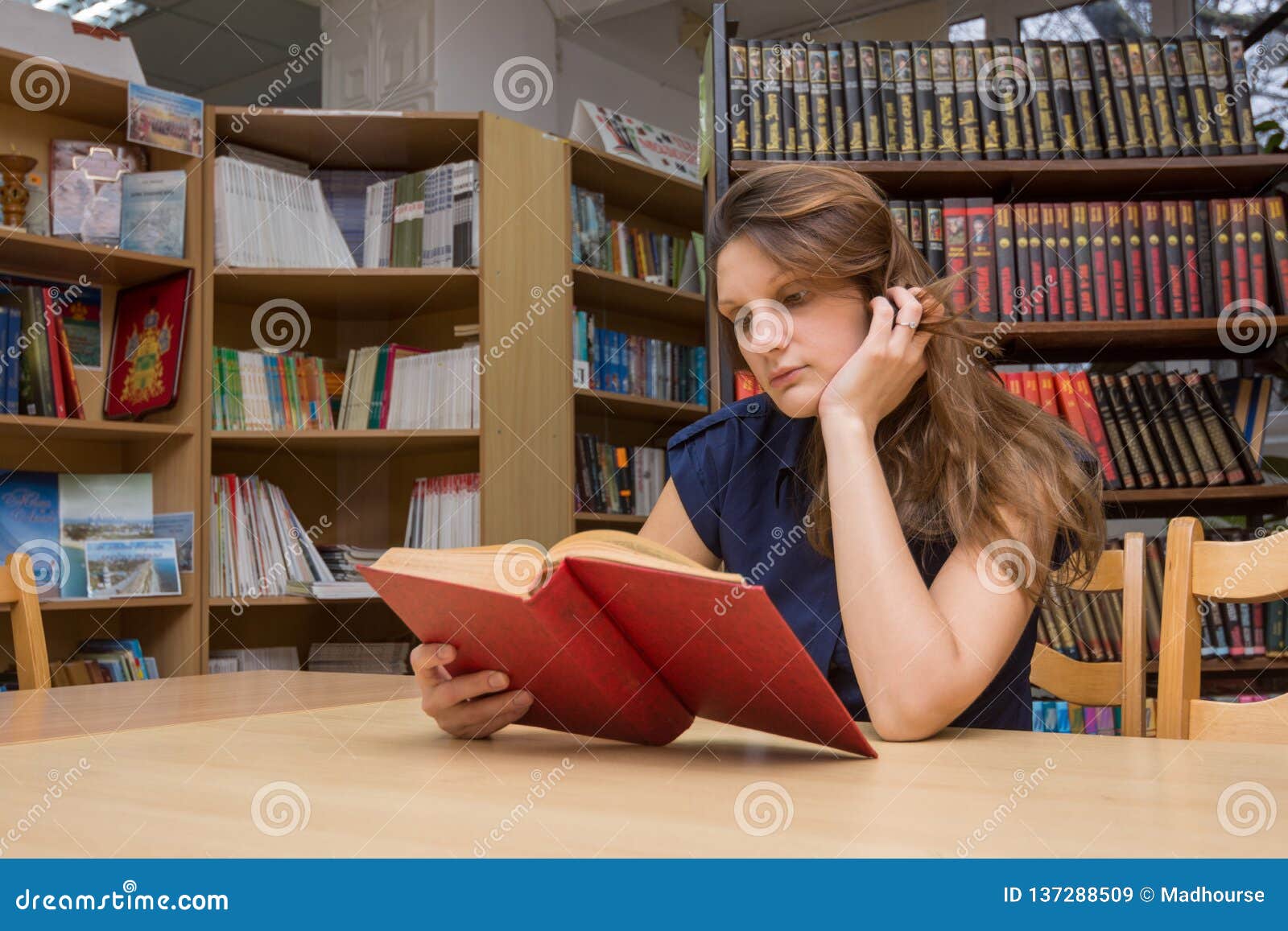 Она сидит в библиотеке. Девушка в читальном зале. Люди в читальном зале. Посетители библиотеки. Люди читают в читальном зале.