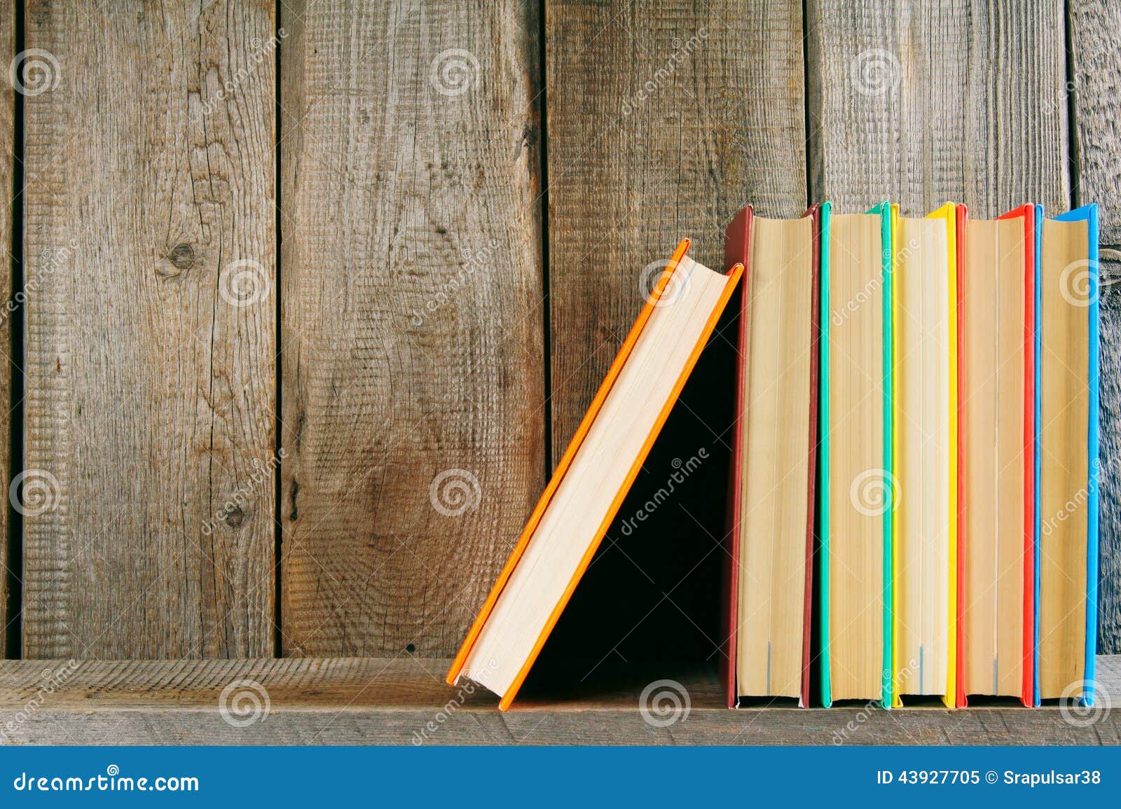 Libri su uno scaffale di legno Su una priorità bassa di legno