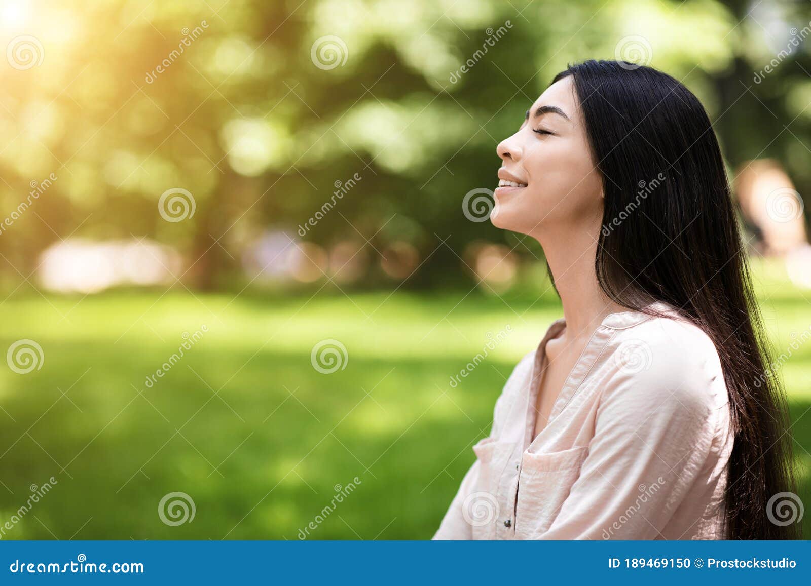portrait of relaxed asian girl breathing deeply with closed eyes in park