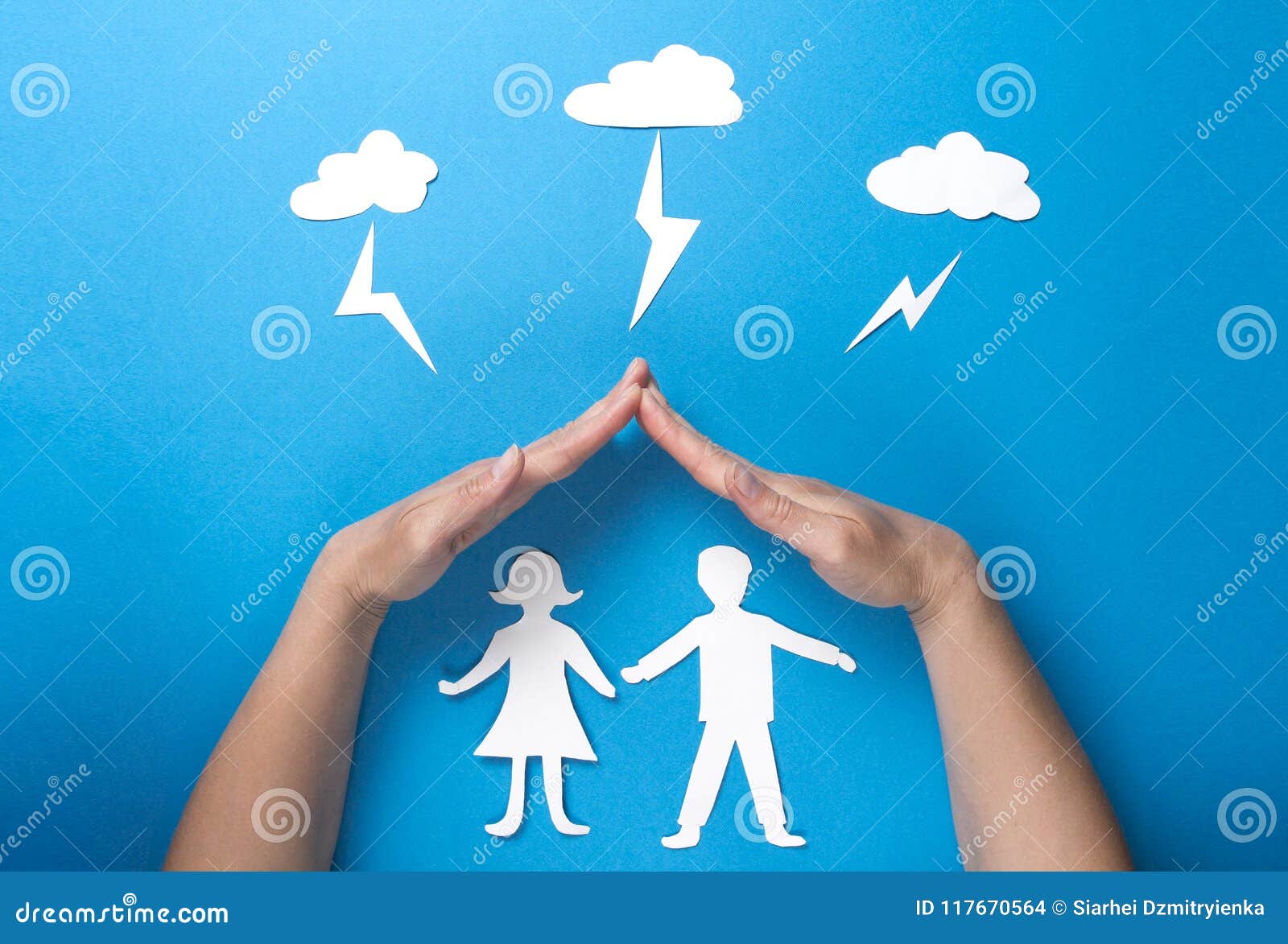 life insurance and family health concept. hands protect paper figures origami from lightning from the clouds on blue background