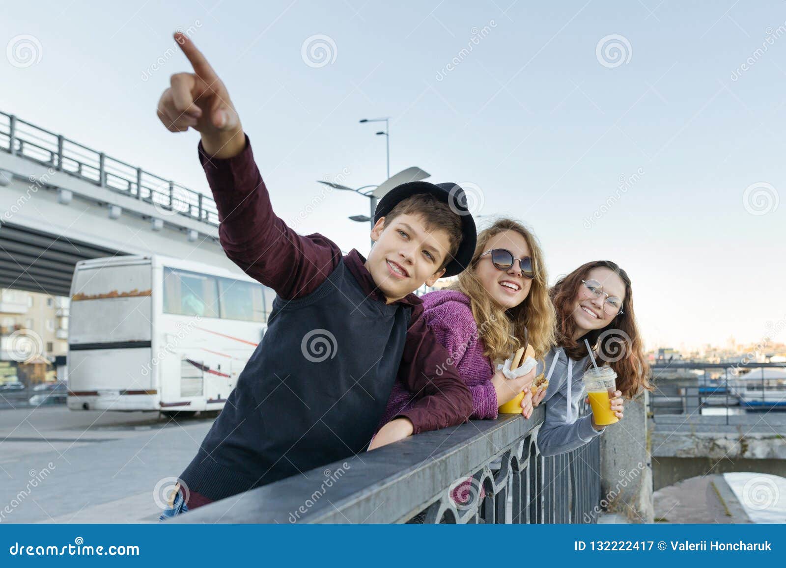 lifestyle of adolescents, boy and two teen girls are walking in the city. laughing, talking children eating street food, having