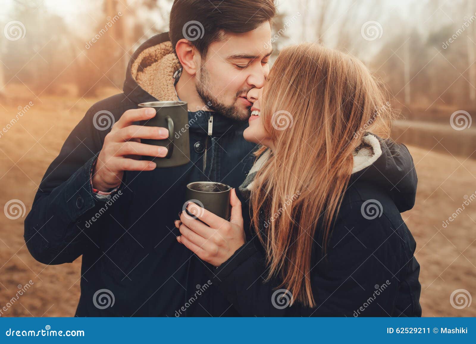 lifestyle capture of happy couple drinking hot tea outdoor on cozy warm walk in forest