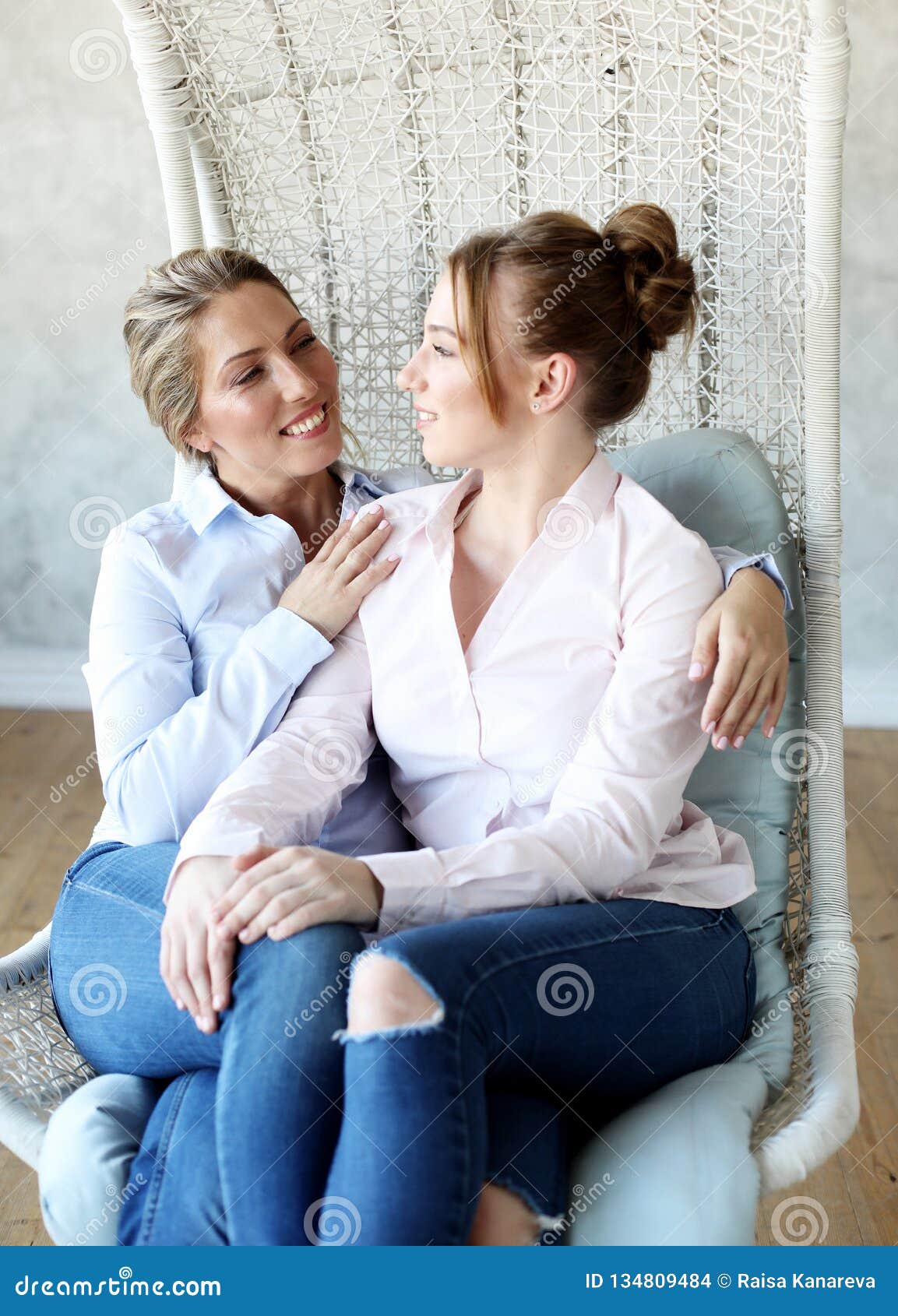 Mature Motherand Daughter Hugging Each Other In Armchair Stock Photo