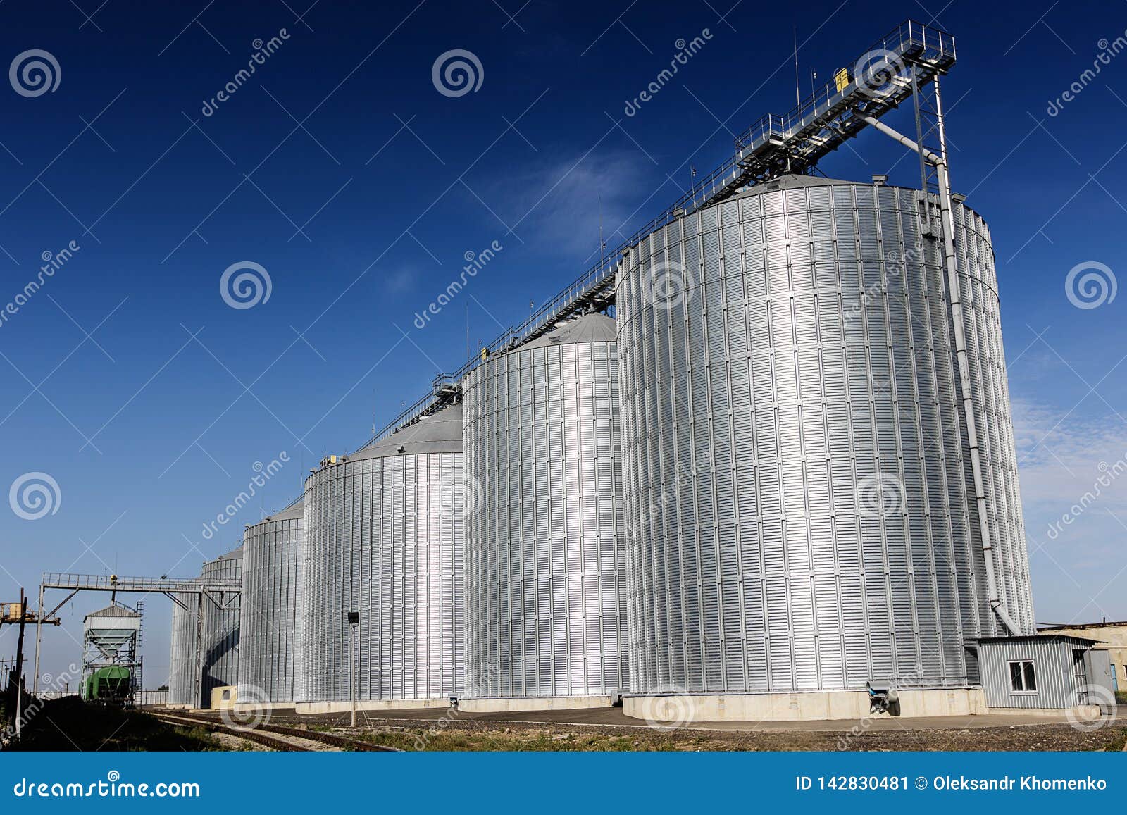 Lift tegen de blauwe hemel. Lift zes groot graanschuuren glanzend aluminium tegen de blauwe hemel