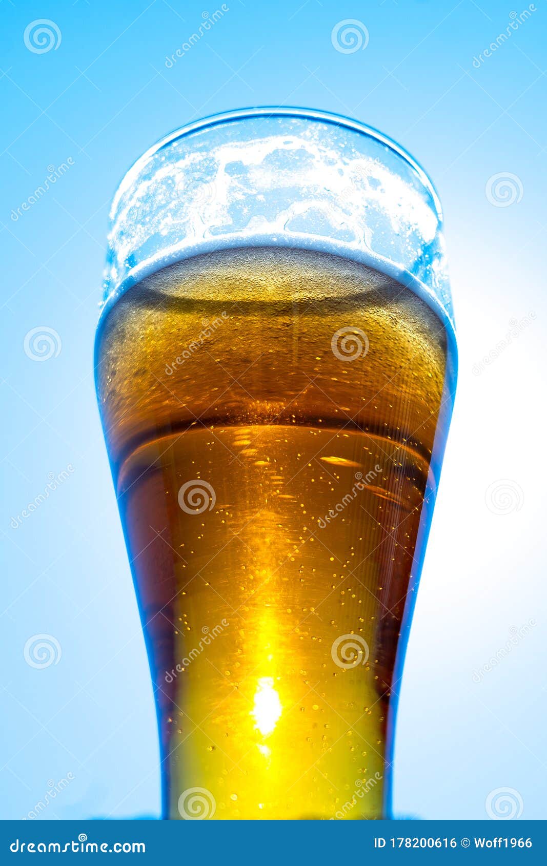 Light Beer in a Glass Goblet on a Background of Blue Sky. Beer Foam on