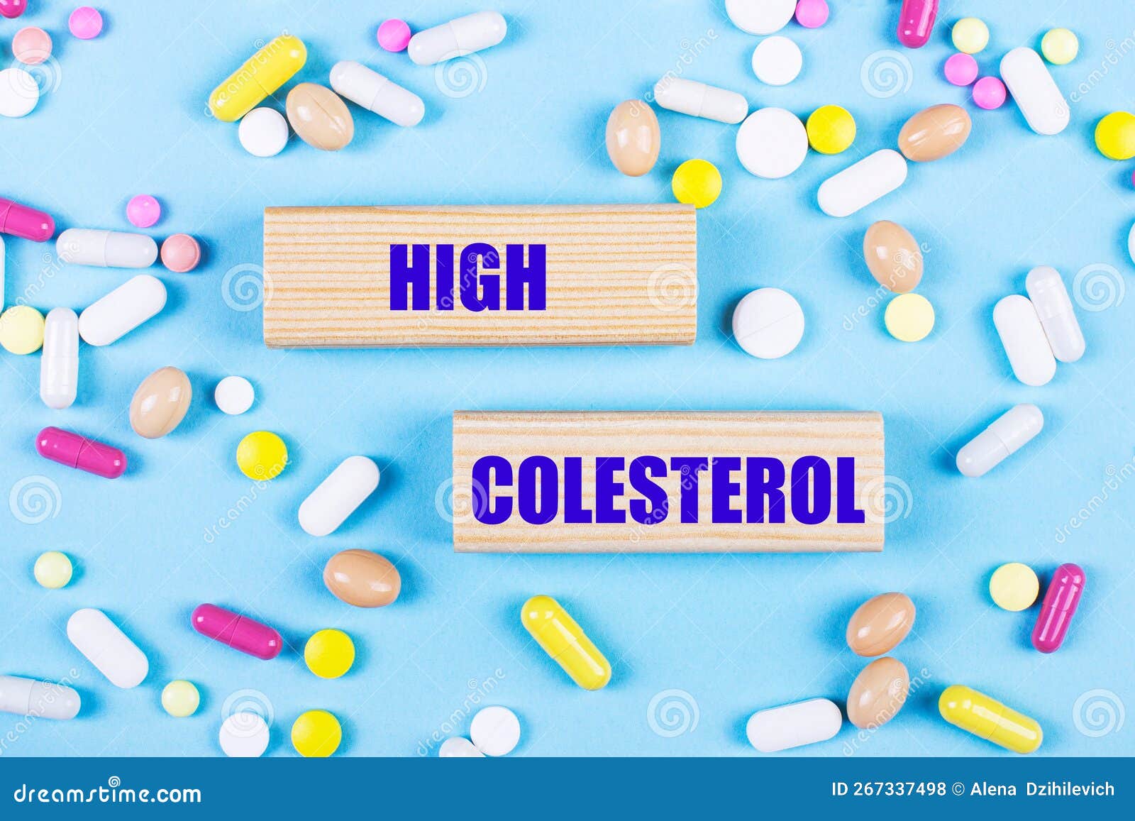 on a light blue background, multi-colored pills and wooden blocks with the text high colesterol. pharmaceutics. medical concept