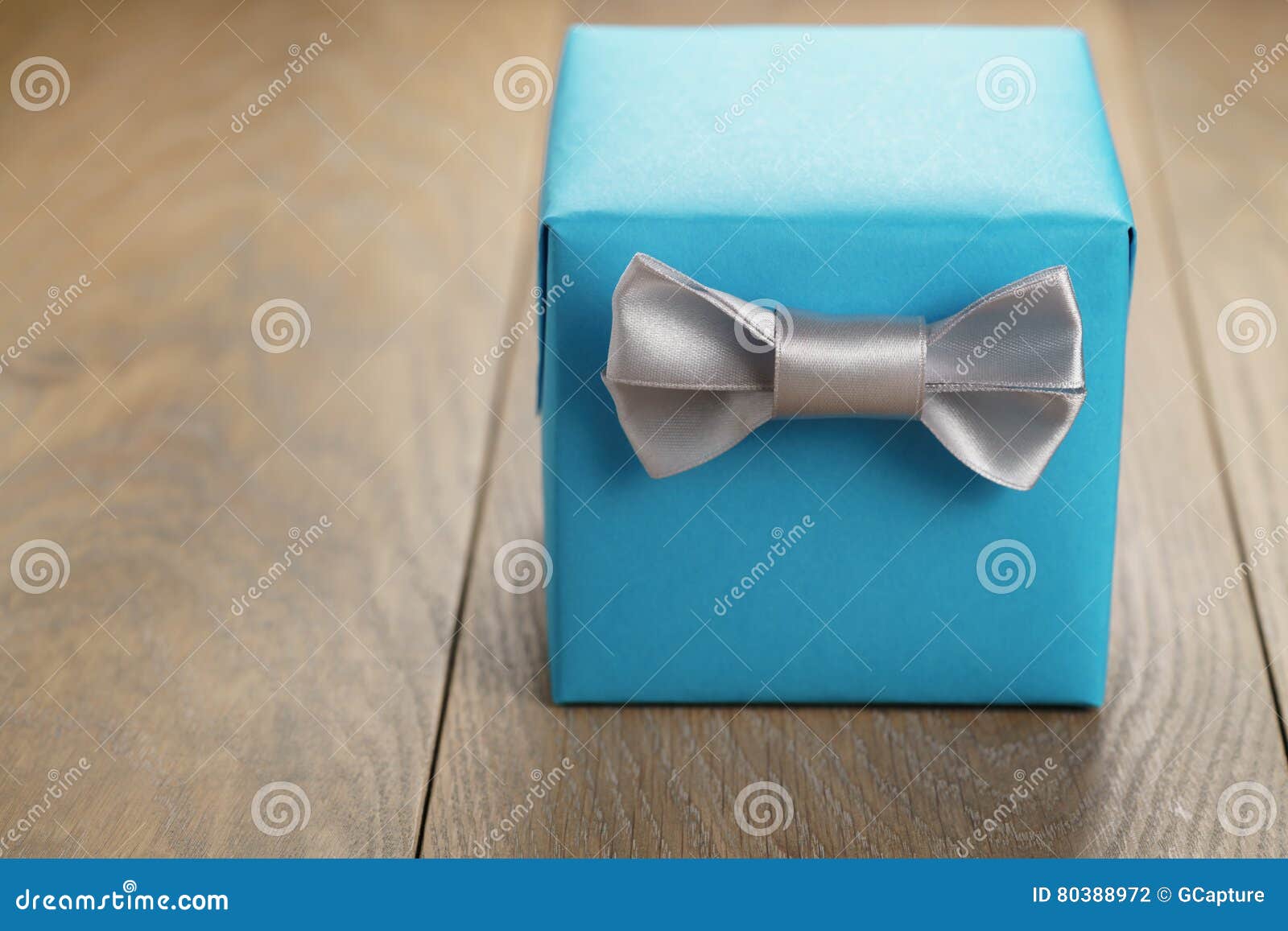 Light Blue Gift Box with Minimalistic Silver Ribbon Bow on Wooden Table