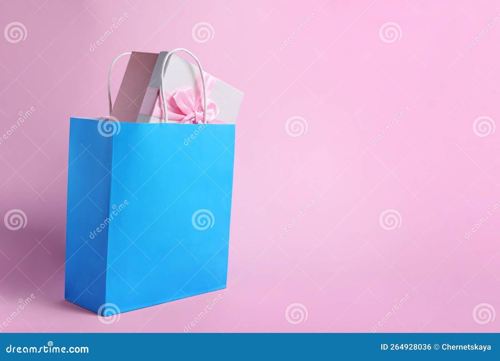 Light Blue Paper Shopping Bag with Gift Box on Pink Background. Space