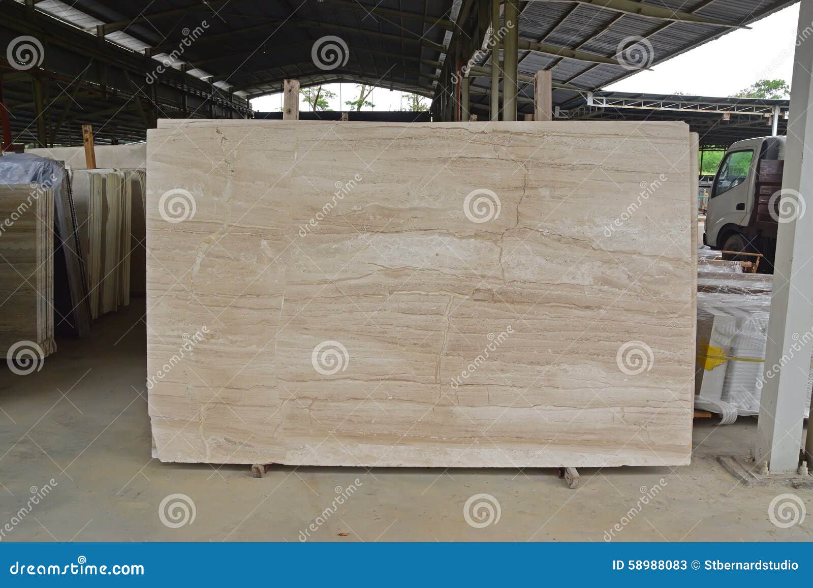 light brown marble slab displayed within a large warehouse