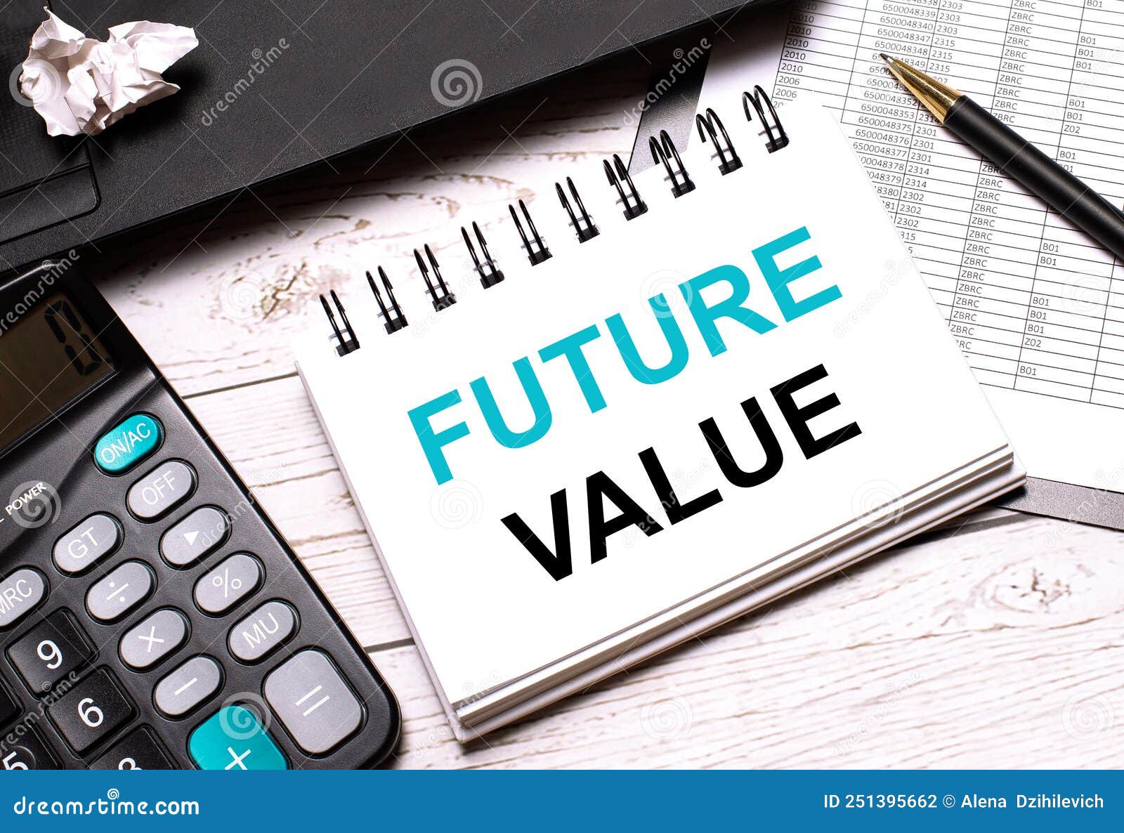 on a light-colored office table is a computer, a black calculator, a pen, and a notebook with the text future value. business