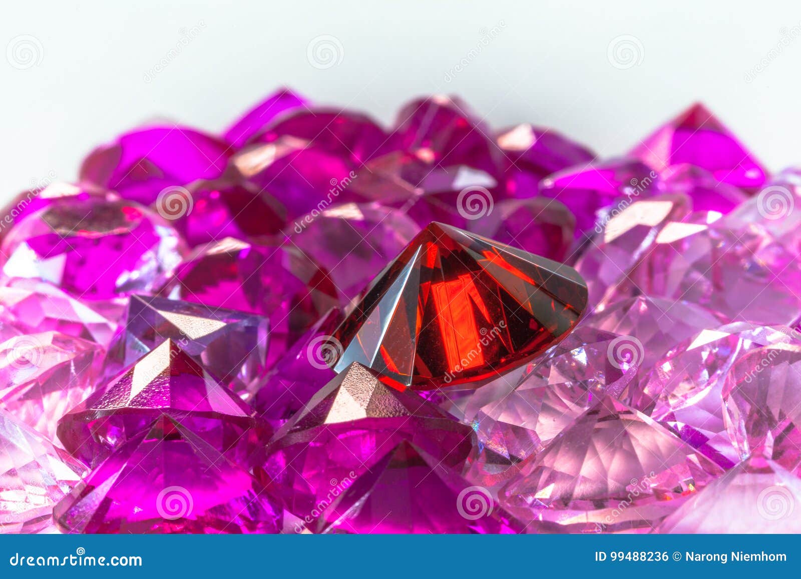 colorful gems on white background. light pendant shine on red diamond. tourmaline pink diamonds around smokey ruby red gemstone.