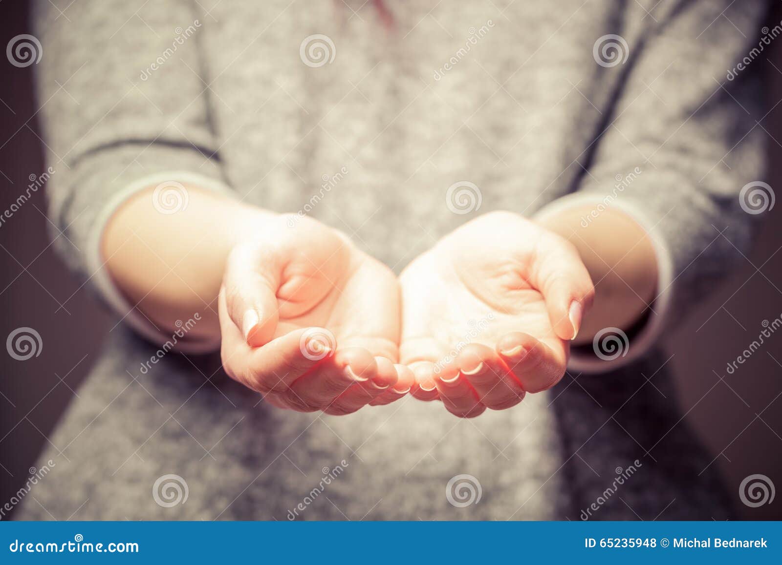 light in young woman's hands. sharing, giving, offering, taking care, protection.