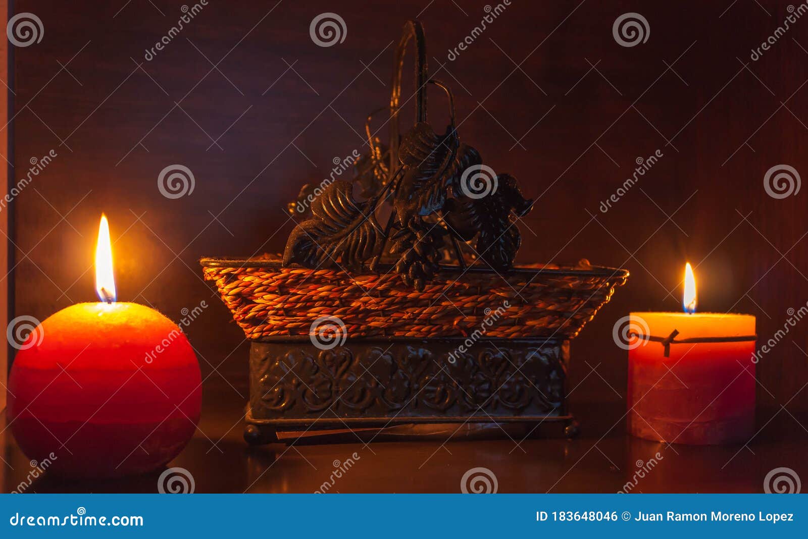 2 lighted candles with a wicker basket behind