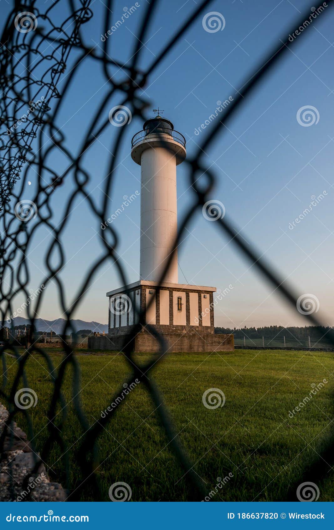 lighthouse of lastres with the fence on the foreground captured in the town of luces, spain