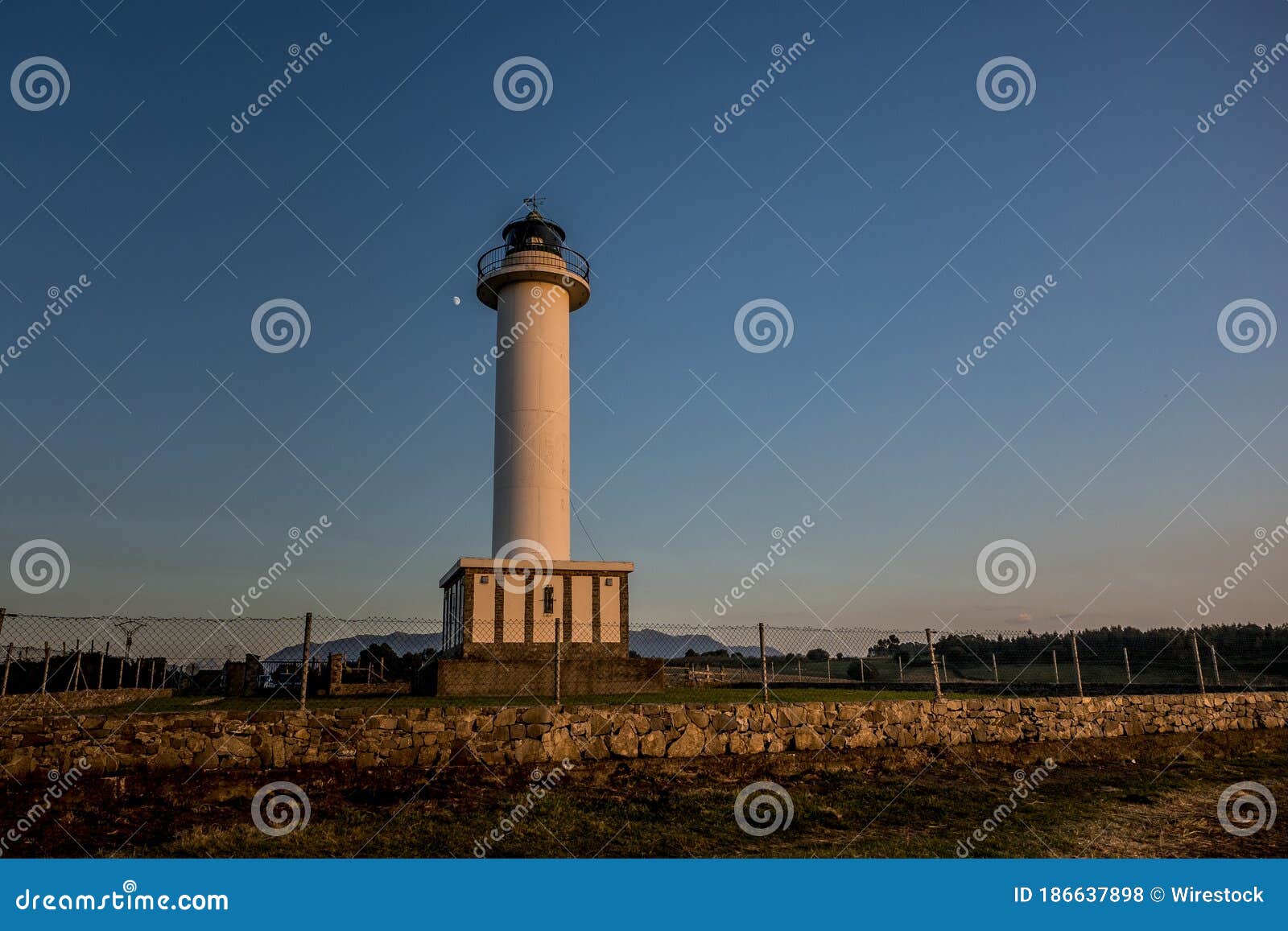 lighthouse of lastres with the fence on the foreground captured in the town of luces, spain