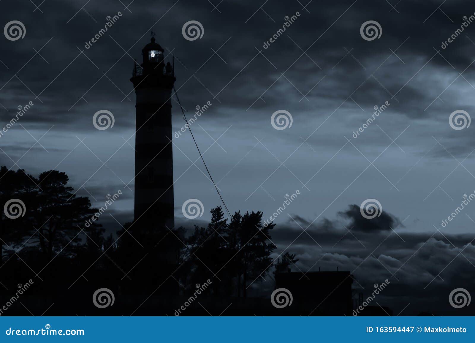 Lighthouse Shines In The Dark With A Dramatic Sky. Silhouette Of Glowing Beacon In Darkness