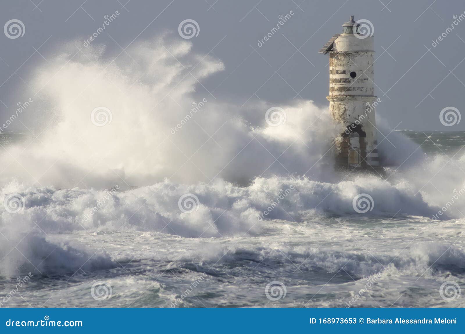 lighthouse shrouded in waves during a storm in the mediterranean.