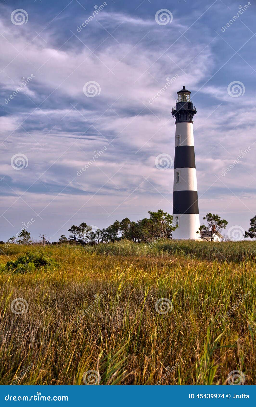 lighthouse surrounded by clouds and marshland