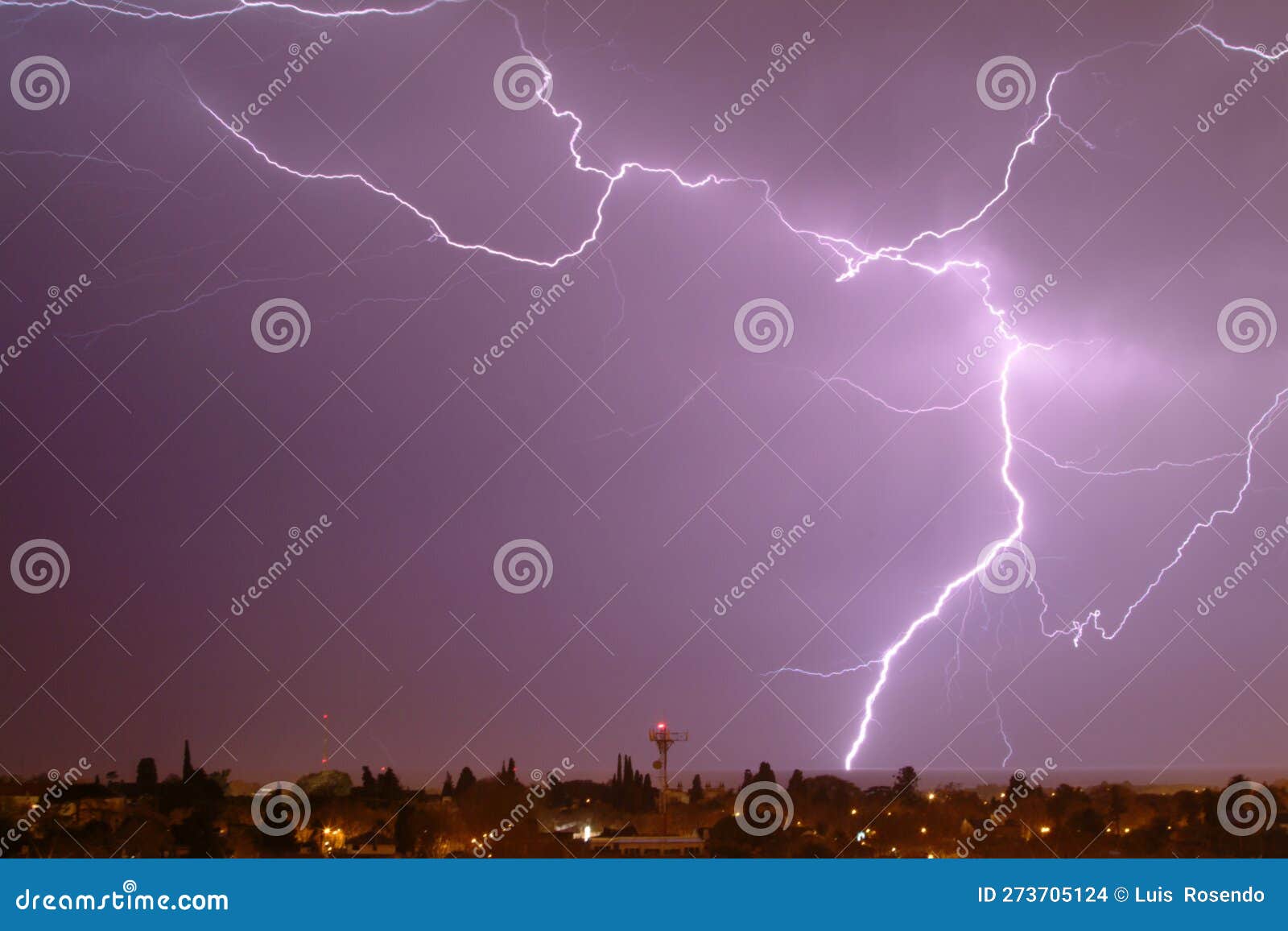 lightning streak from a thunderstorm cloud at night in a rural setting. there are multiple lightning strikes coming from the