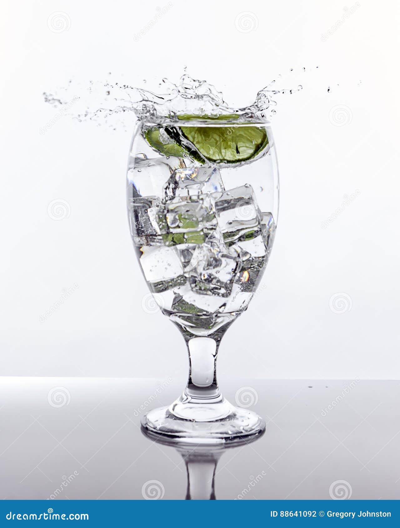 Lime splashes into glass of water. A lime sliced makes a splash after being dropped into a glass of ice water.