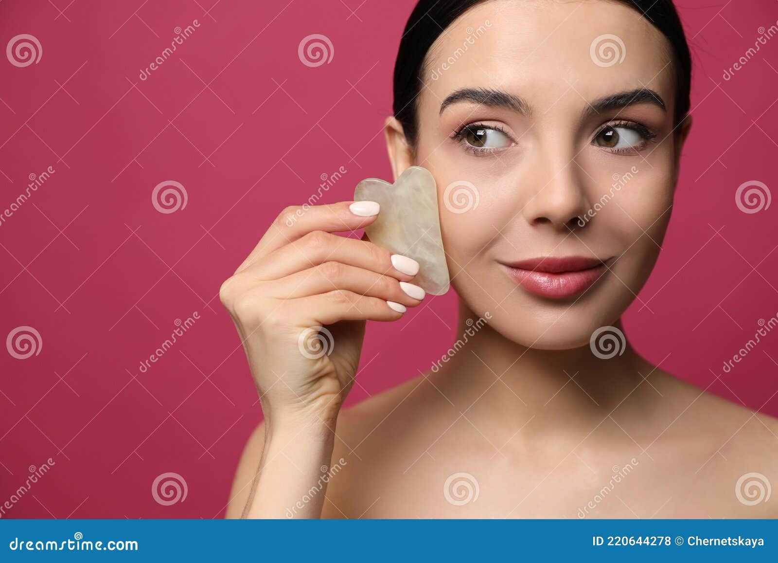 Linda Jovem Fazendo Massagem Facial Com A Ferramenta Gua Sha Em Fundo Cor De Rosa Foto De Stock