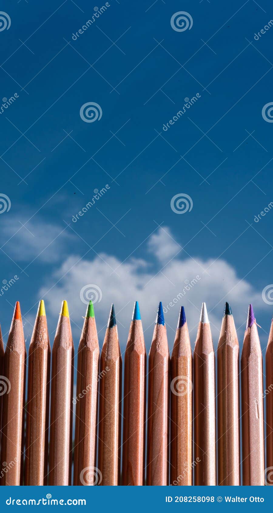 Line of Colored Crayons on a Blue Sky with Clouds Stock Photo Image