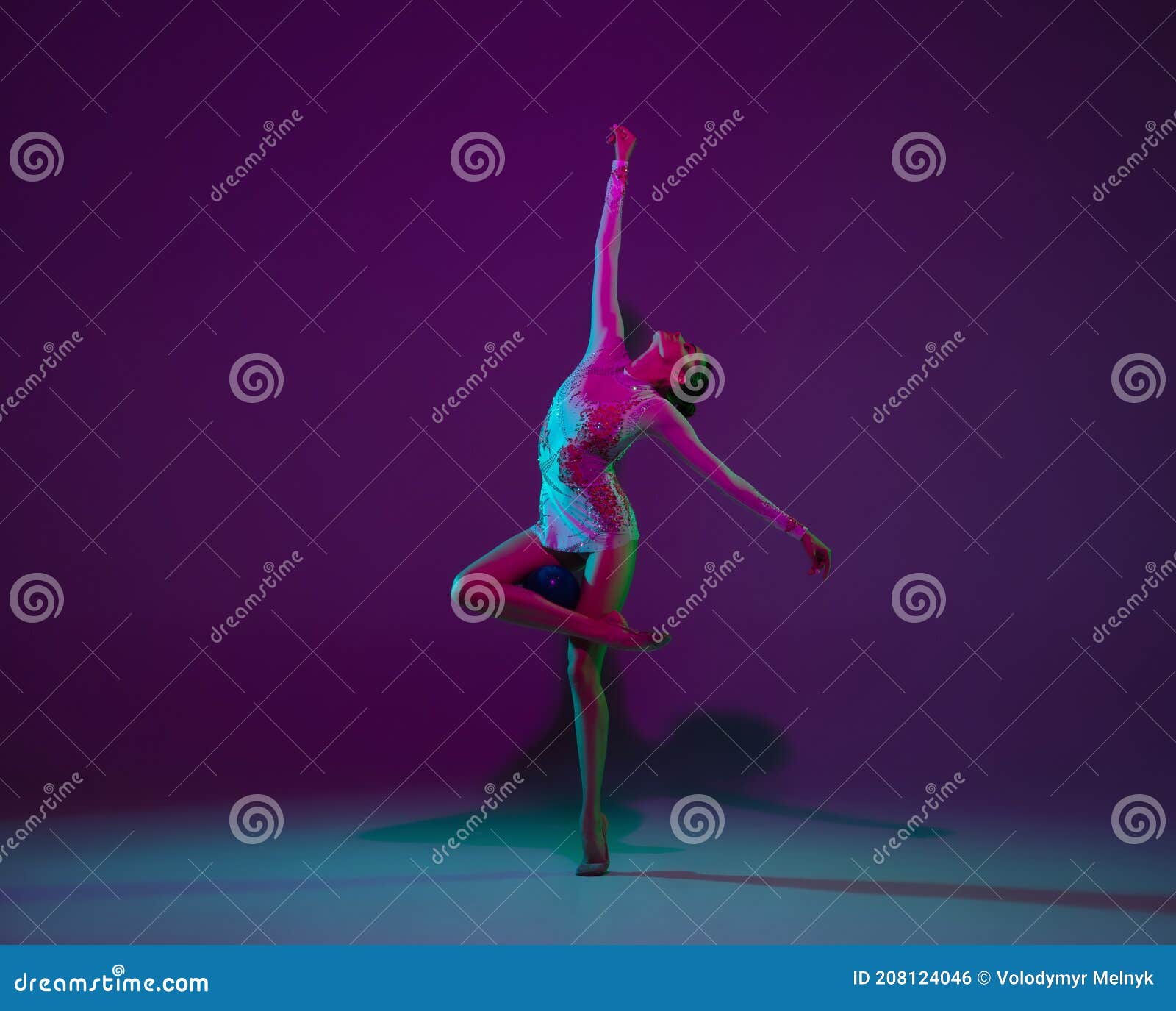 young female athlete, rhythmic gymnastics artist on purple background with neon light. beautiful girl practicing with
