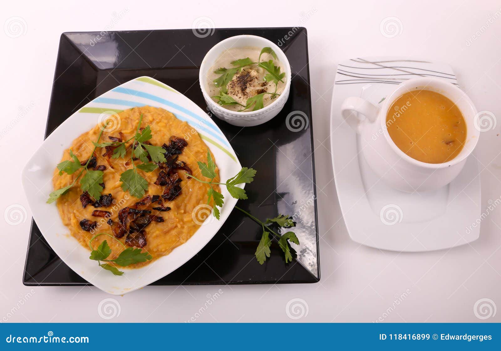 Gelbe Linsenmahlzeit mit Suppe auf Platte über weißem Hintergrund