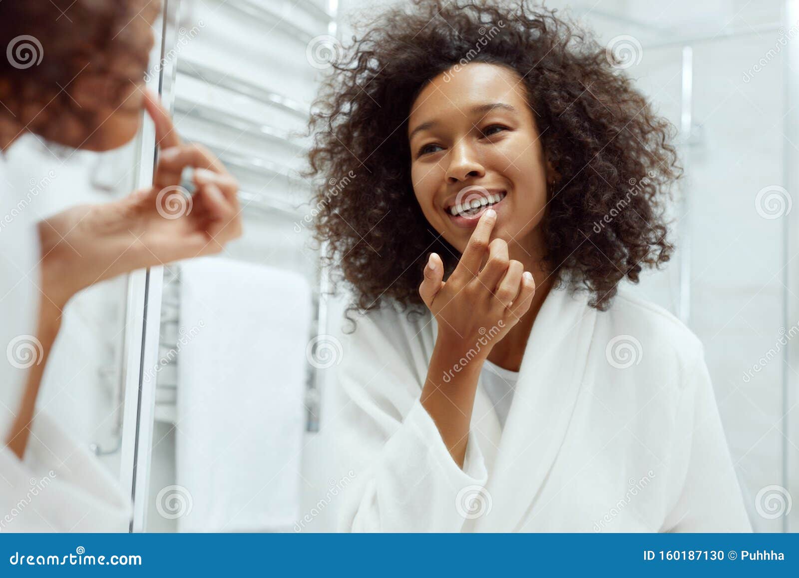 lips skin care. woman applying lip balm in bathroom portrait