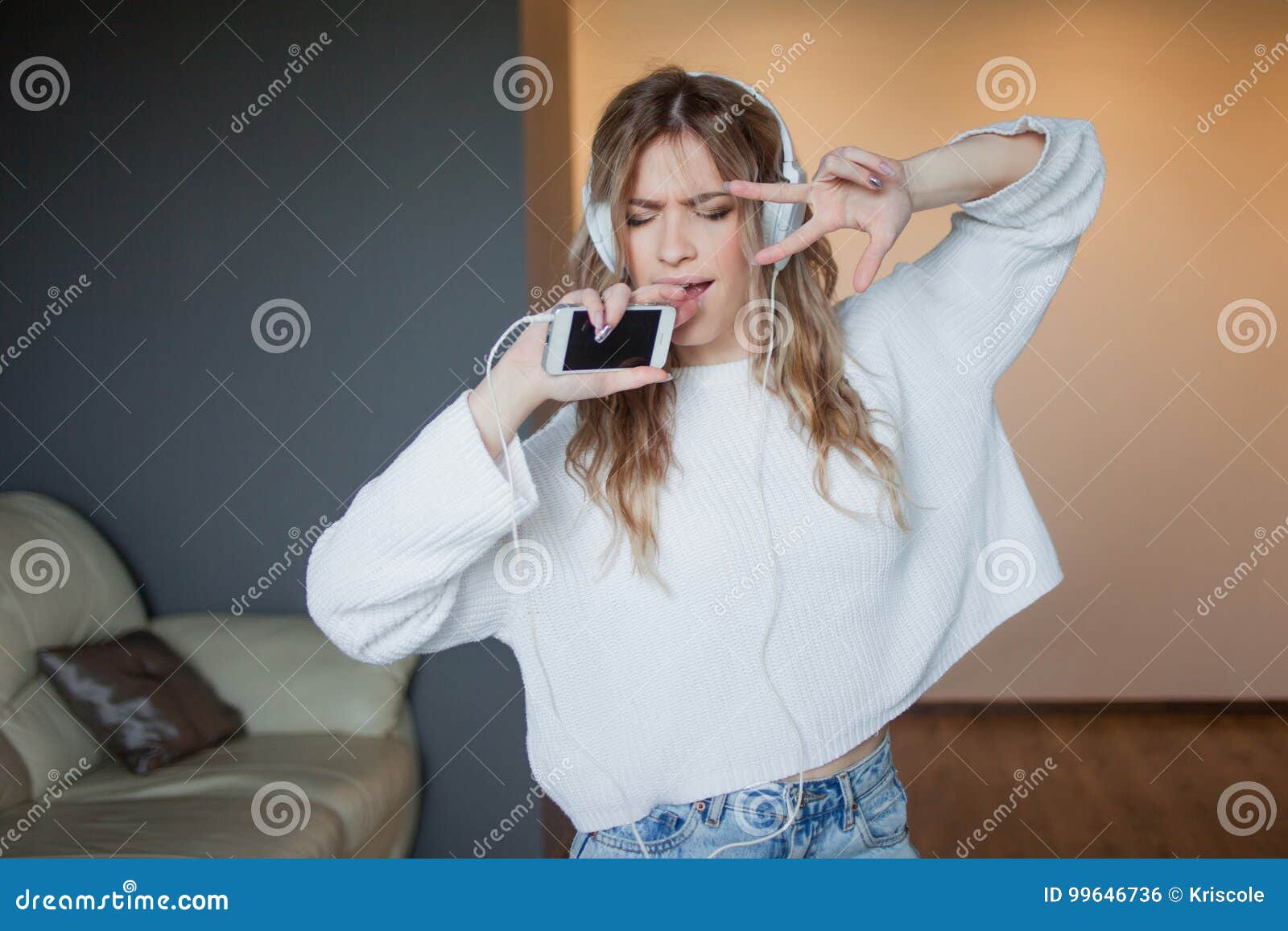 listen to music, sing into the phone as the microphone. portrait of happy young woman at home