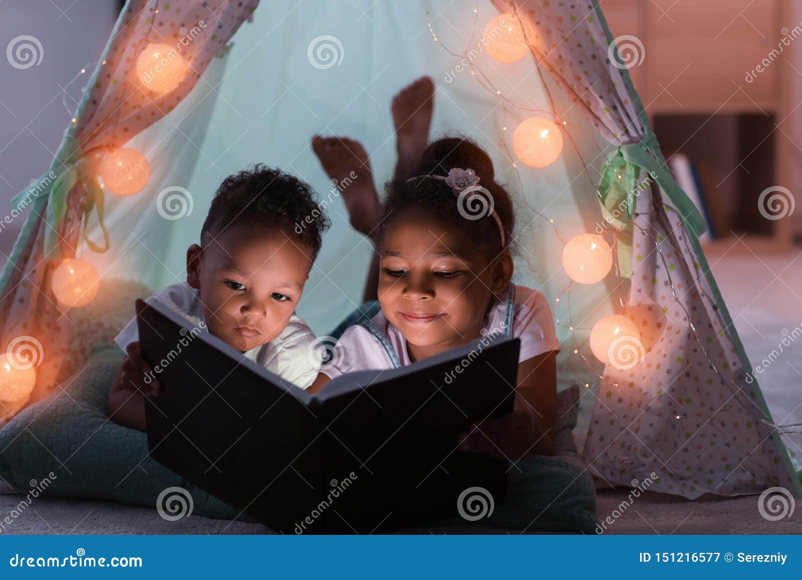 little african-american children reading bedtime story in hovel
