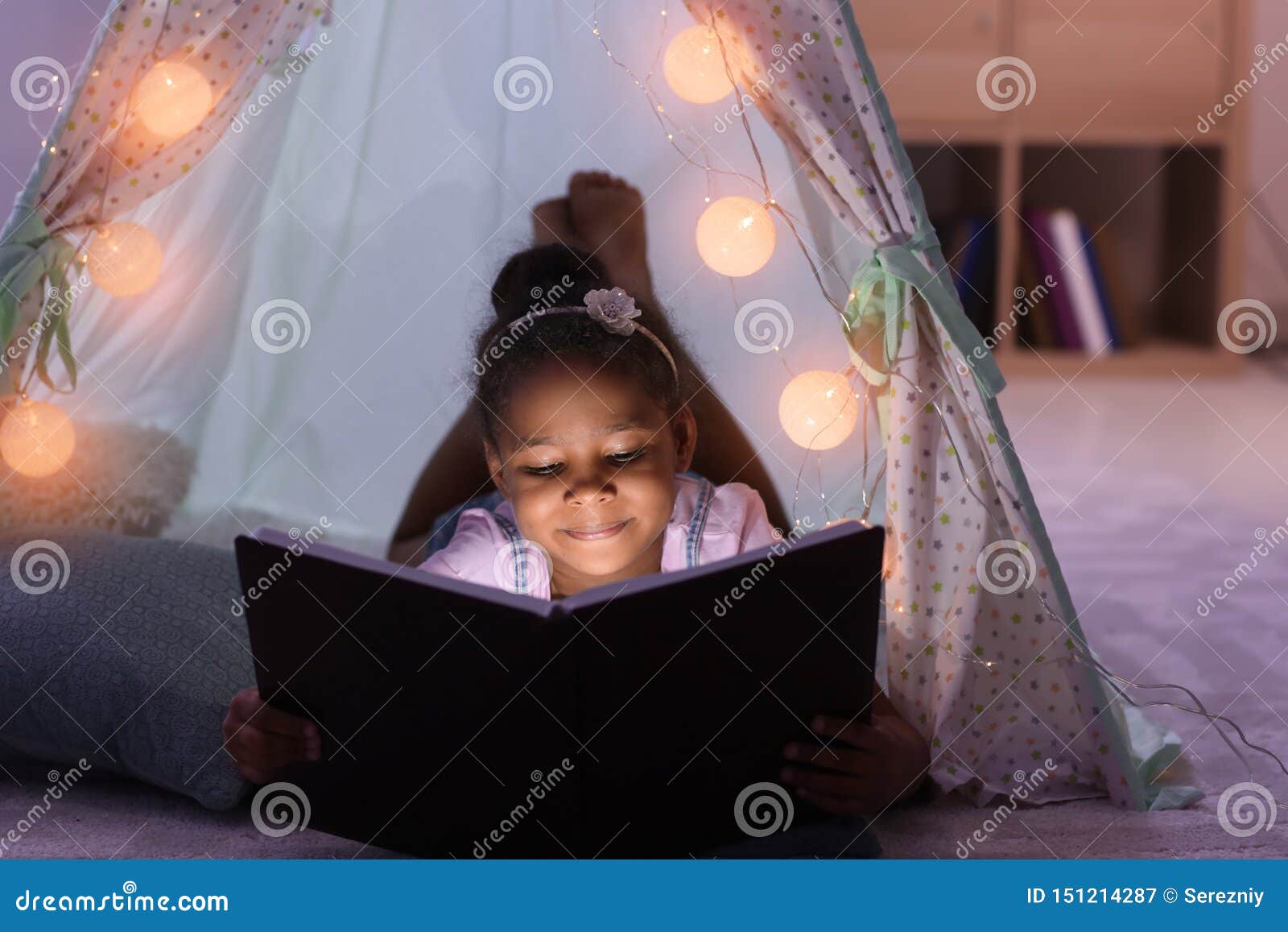 little african-american girl reading bedtime story in hovel