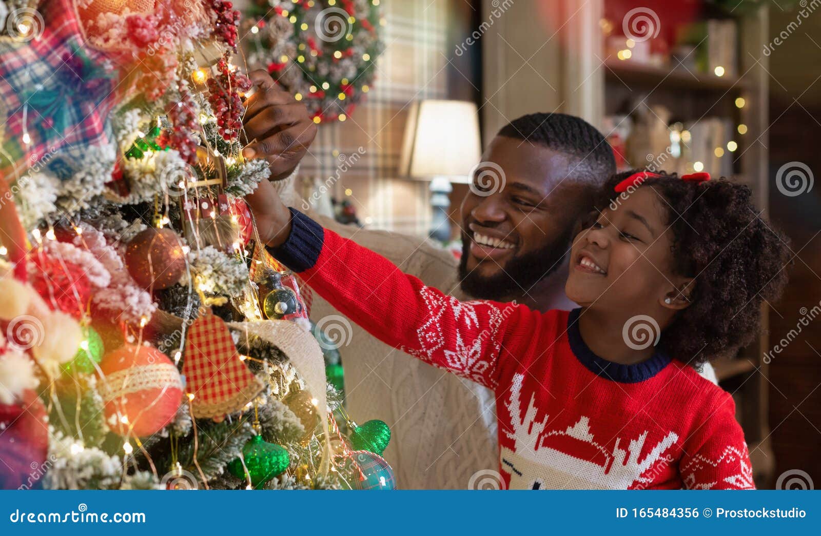 little afro girl helping daddy to decorate family christmas tree