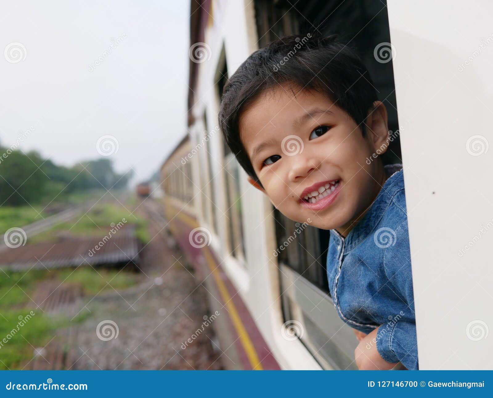 little asian baby girl enjoys sticking her head out of a train window and having the wind whips against her face