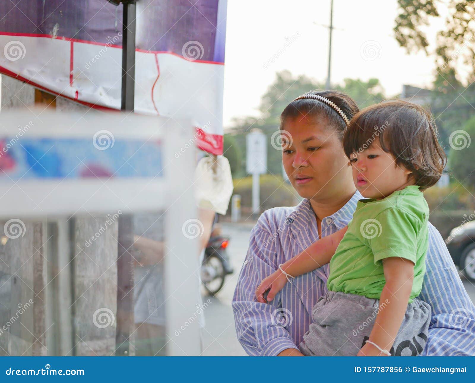 little asian baby girl together with her mother watching food vender selling / cooking street food