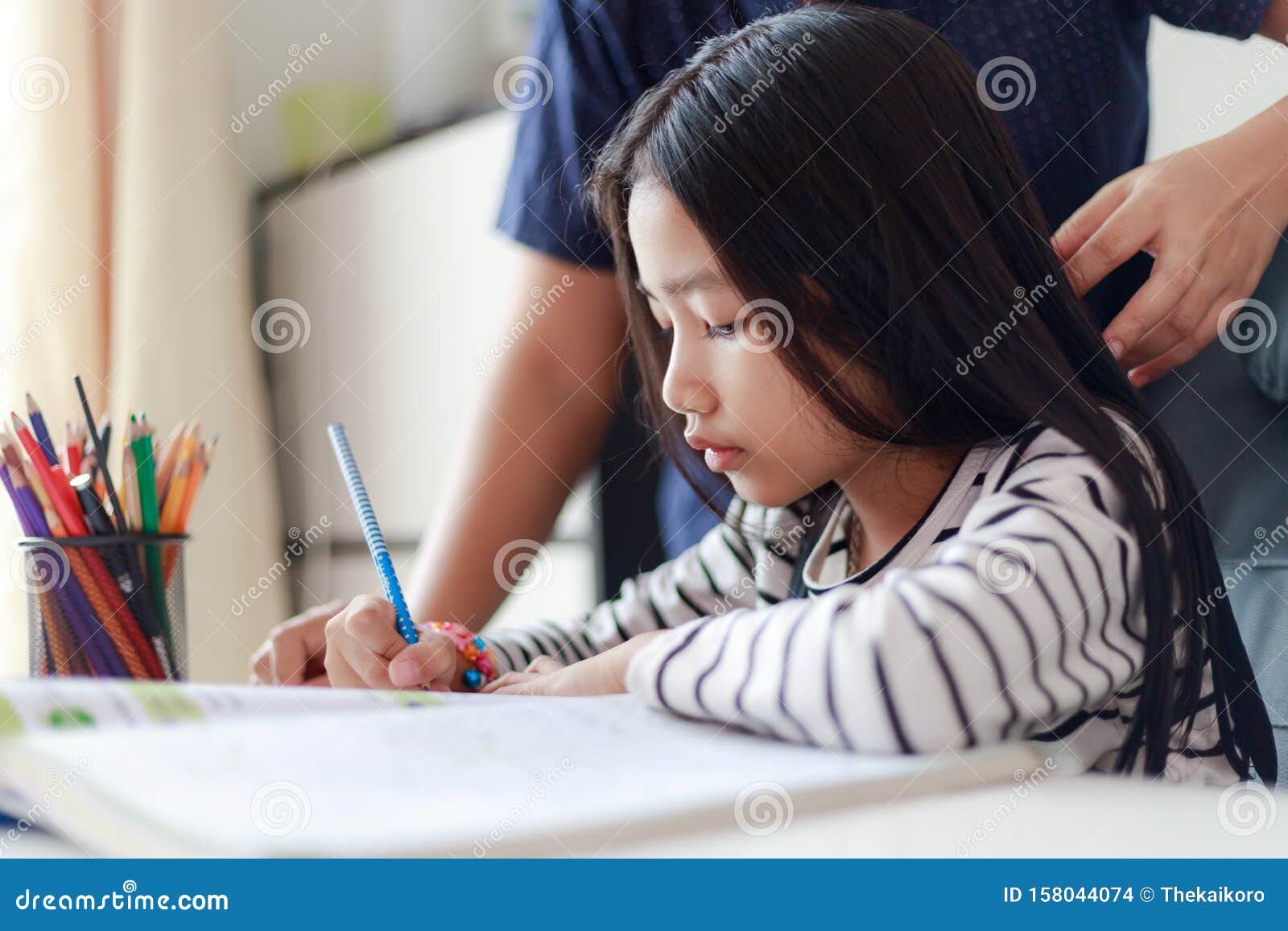 Little Asian Girl Doing Homework With Mother For Self Learning And