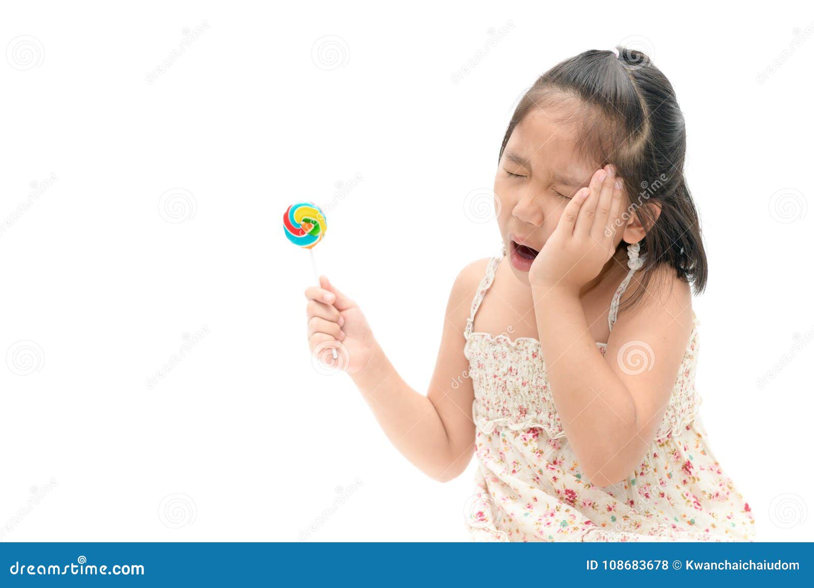 Little Asian Girl Suffering from Toothache and Holding Candy Stock