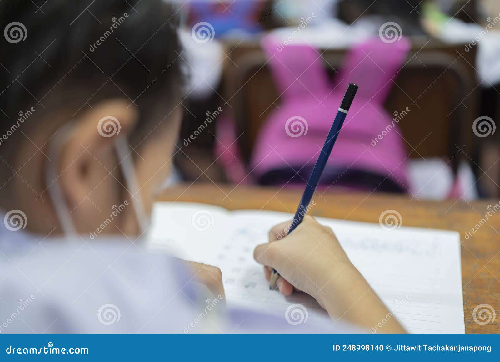 little asian school girl writing notebook homework with pencil