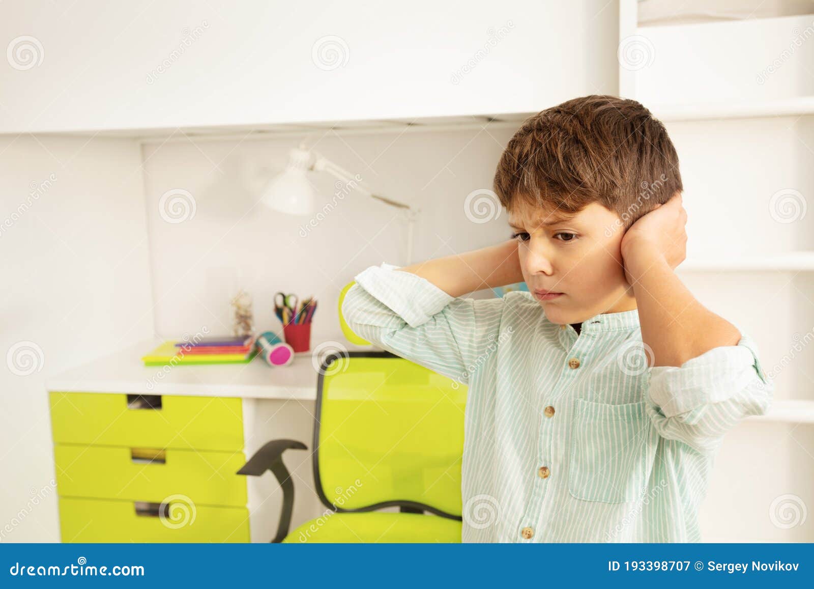 autistic boy with sad look close ears from noise