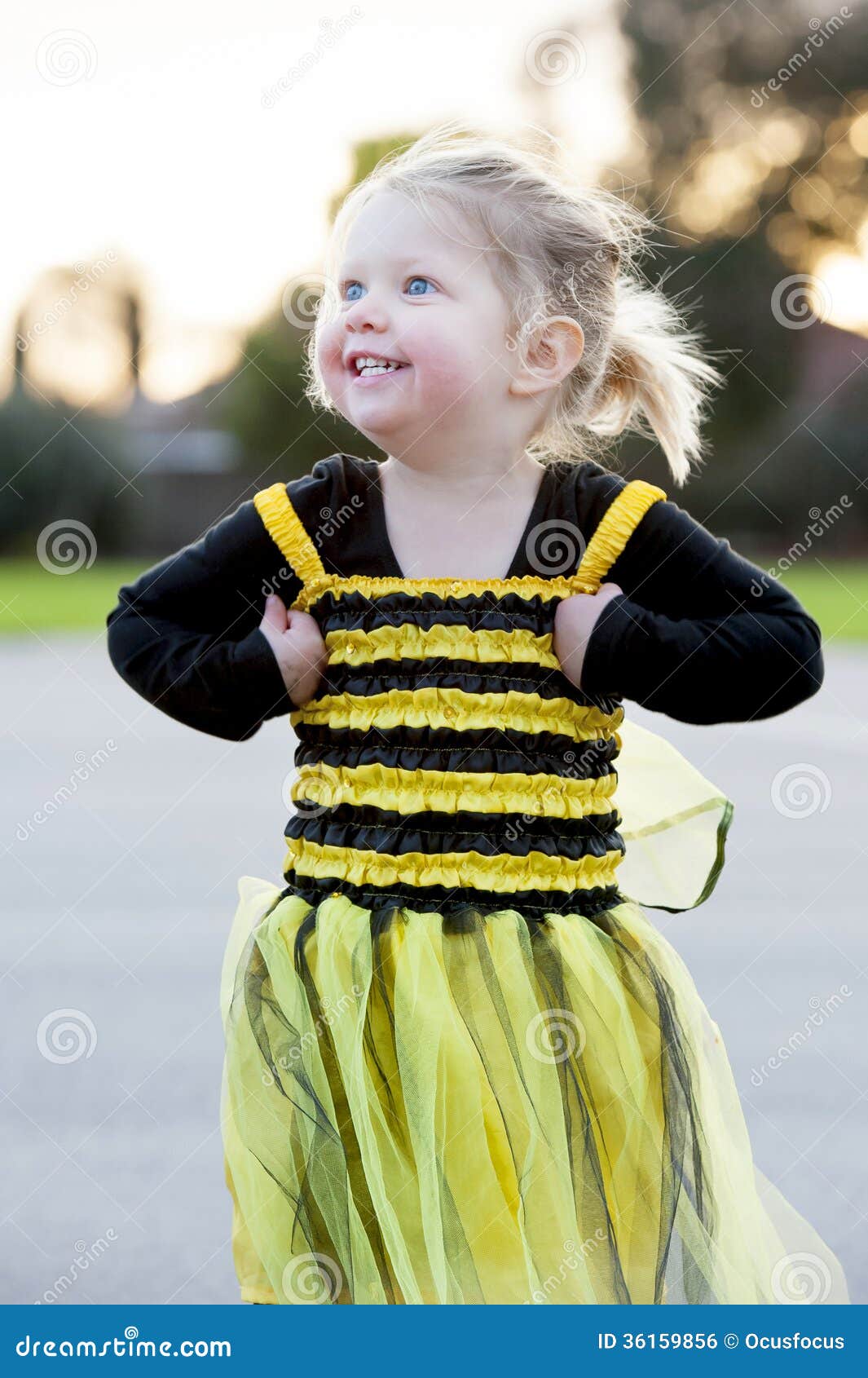 little blond girl in bee costume dancing outdoors