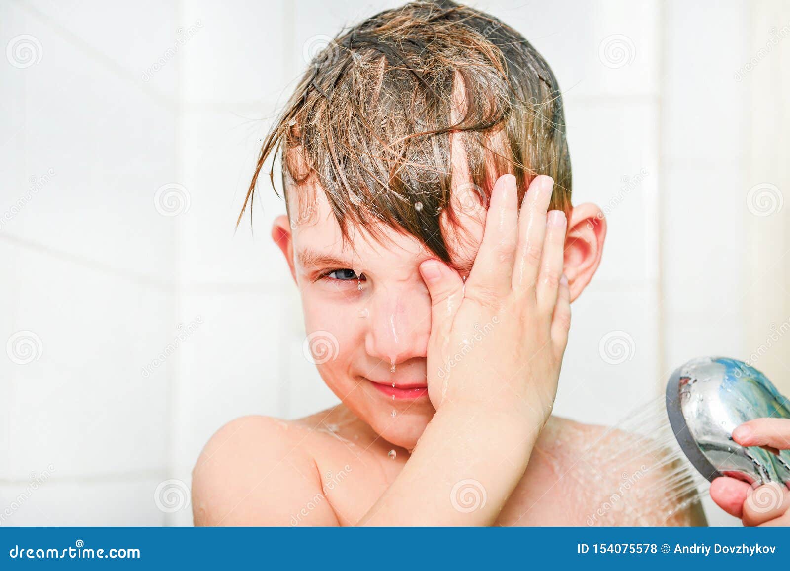 A Little Boy Bathes in the Bathroom Under the Shower Stock Photo
