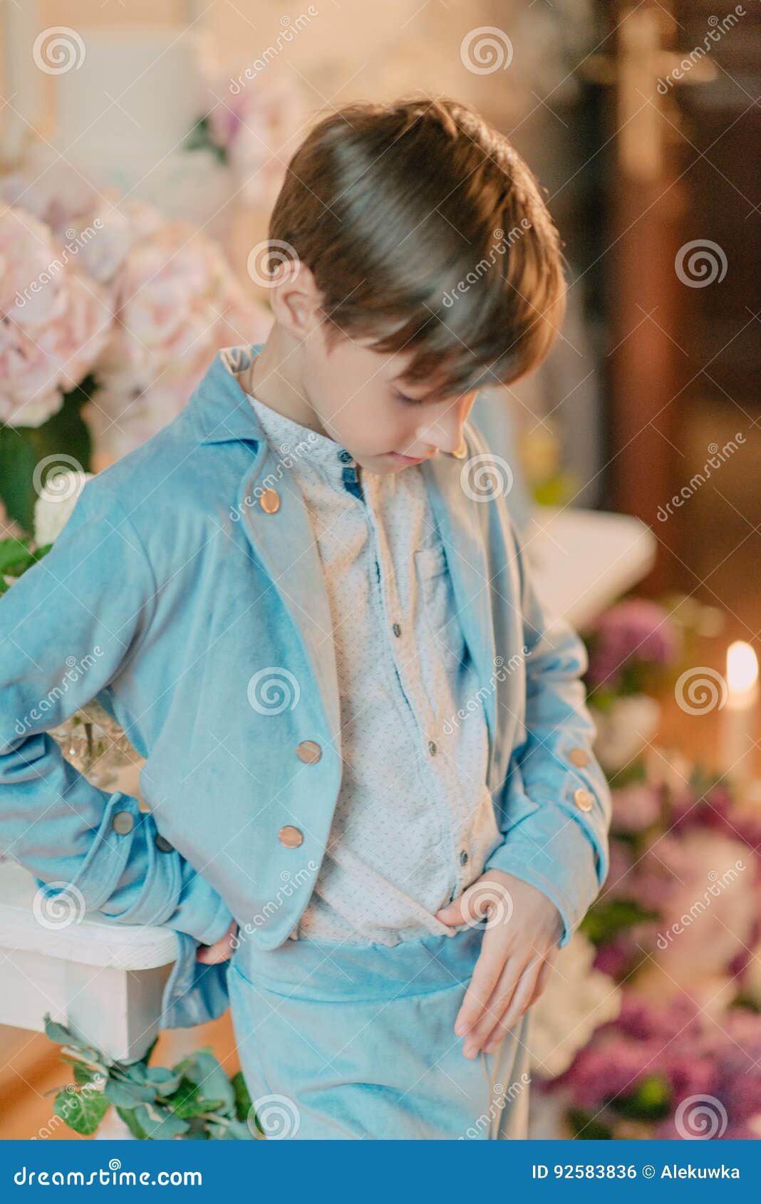 The Little Boy in the Blue Suit in the Studio with Flowers Stock Photo