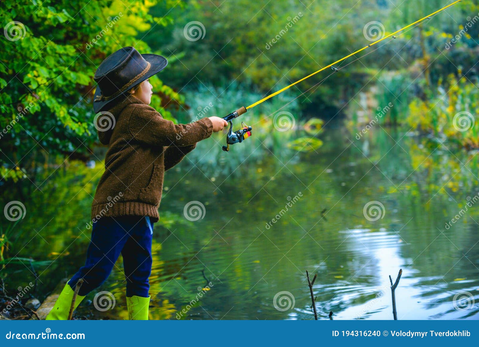 Little Boy Child Catching a Fish. Kid with Fishing Rod at Lake