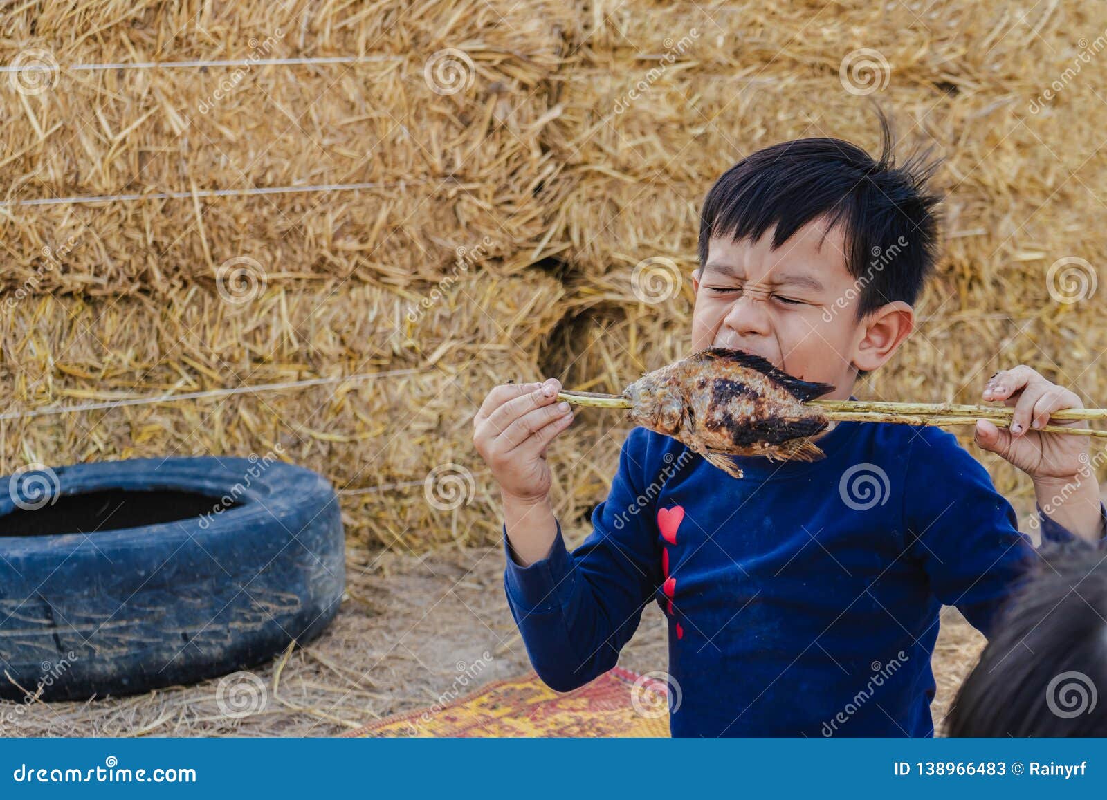 Little Boy Eating Fried Fish on the Field Looking Happiness Stock Image