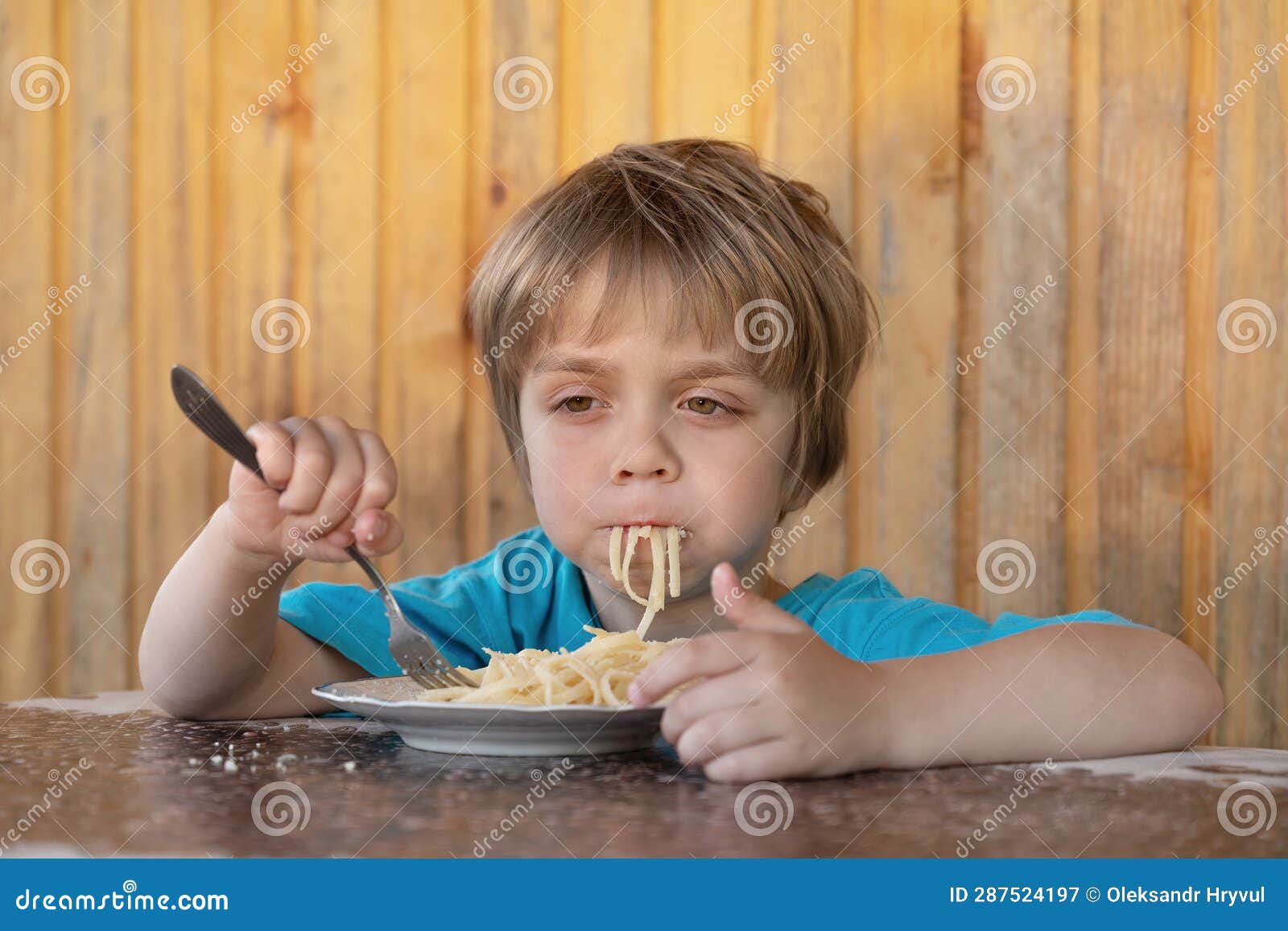 A Little Boy Eats Spaghetti with Parmesan Cheese. he is Dreamy Stock