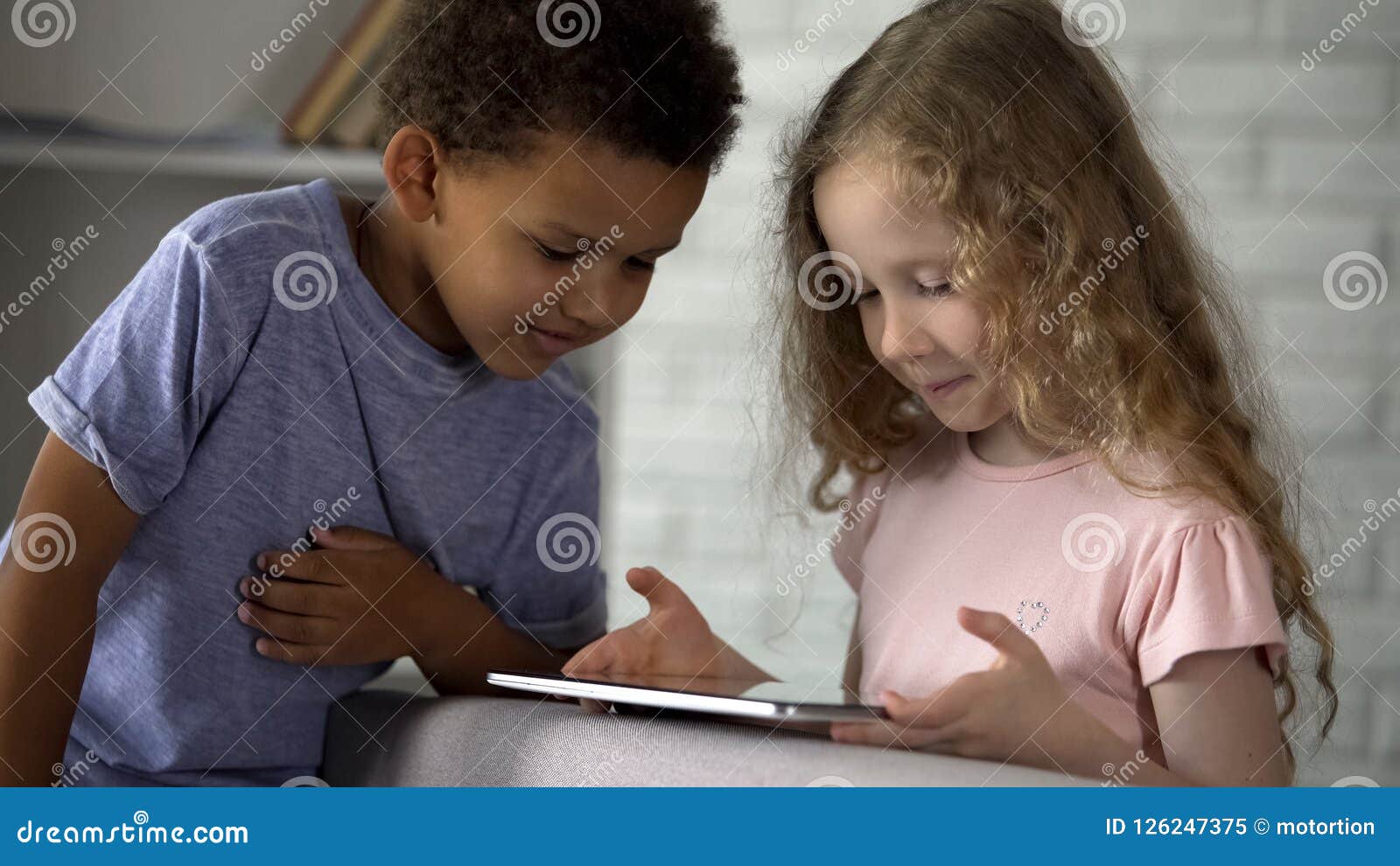 little boy and girl watching movie on tablet at kindergarten, early development