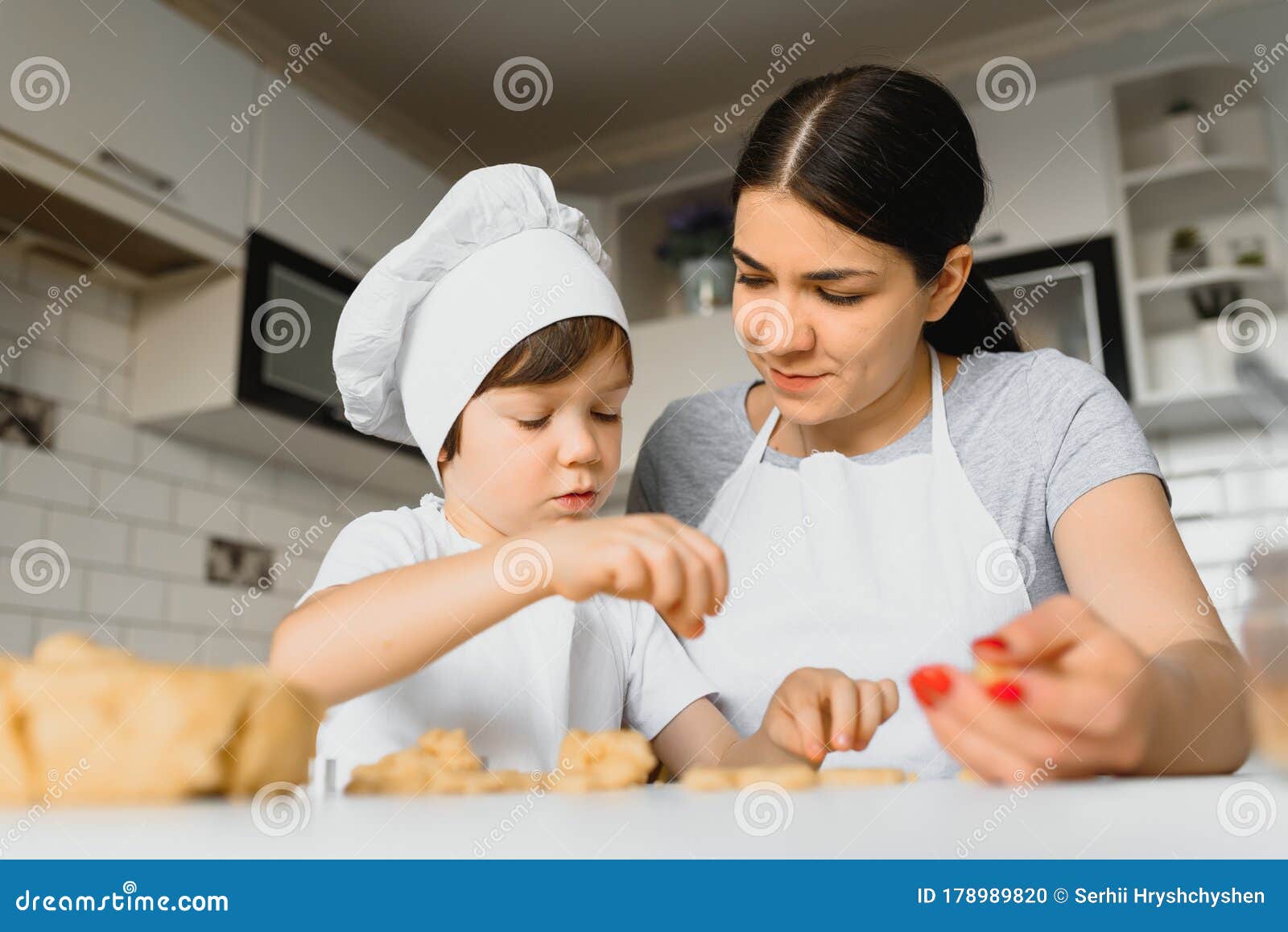 Little Boy Helping His Mother With The Baking In The Kitchen Standing