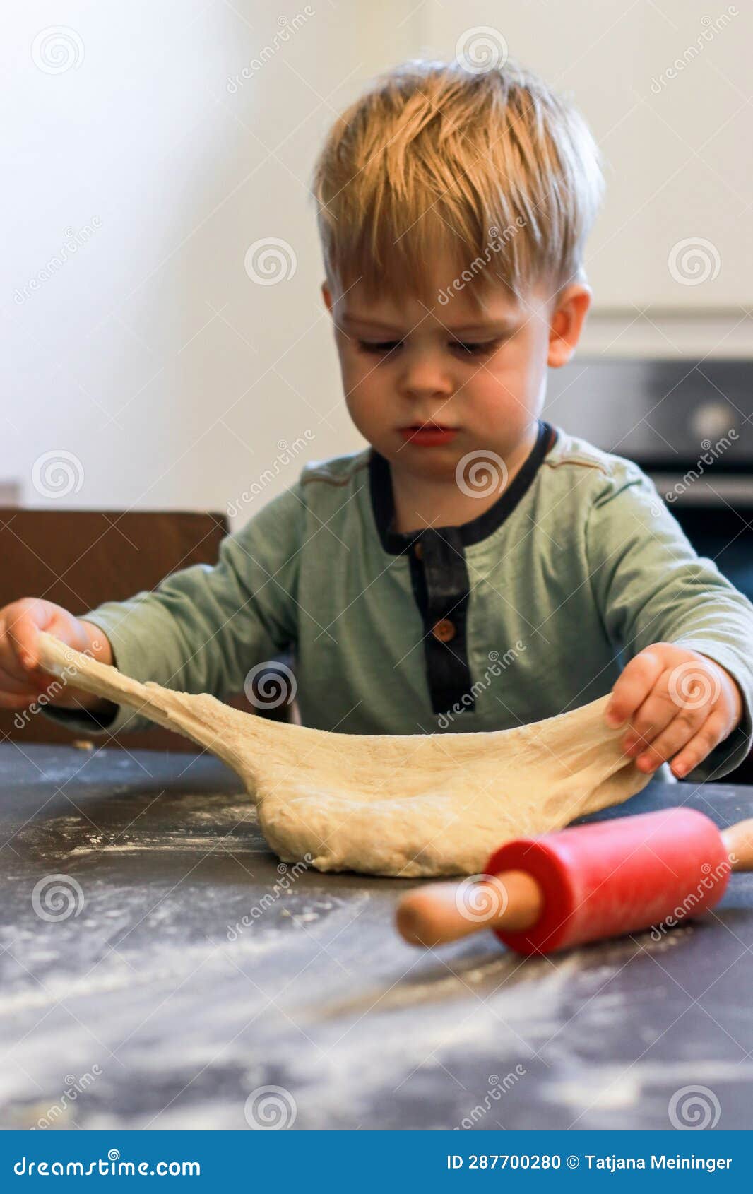 A Little Boy Knead and Play with Dough, a Red Rolling Pin on the Table
