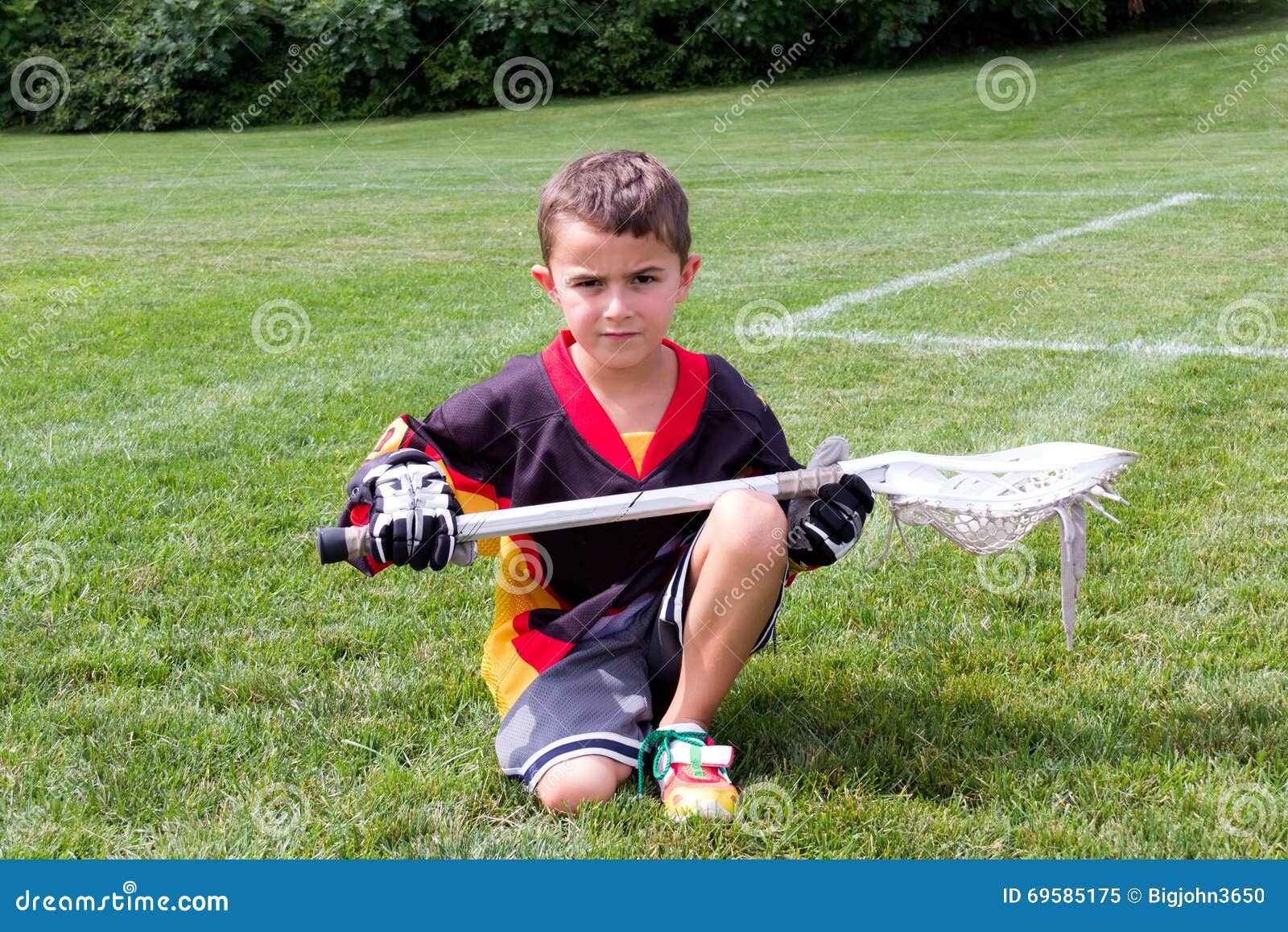Little Boy Lacrosse Player in the Park Kneeling Down and Posing Stock